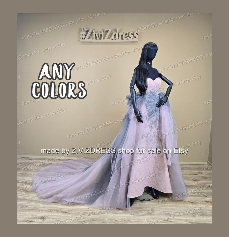 May include: A strapless, floor-length gown in soft pink with a flowing, layered skirt and train. The dress features a gray accent and is displayed on a mannequin. The text "ANY COLORS" is visible.