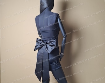May include: A black sleeveless dress with a large black satin bow at the waist. The dress is fitted and has a short skirt.