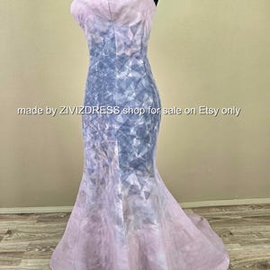 May include: A floor-length, strapless gown with a mermaid silhouette. The dress features a watercolor-like design in shades of lavender and blue, with a geometric pattern overlaying the bodice. The text "made by ZIVIZDRESS shop for sale on Etsy only" is visible.