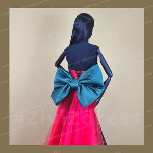 Puede incluir: Un vestido de tul rojo con un gran lazo de satén verde en la espalda. El vestido está hecho por la tienda ZIVIZDRESS y está a la venta en Etsy.