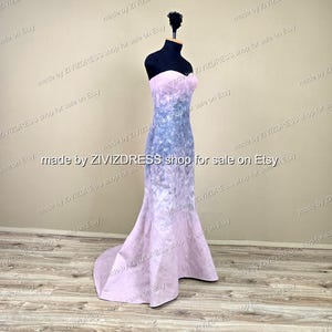 May include: A strapless, floor-length gown on a black mannequin. The dress features a gradient design, transitioning from a light pink bodice to a blue and purple patterned midsection, and back to pink at the flared hem. The text "made by ZIVIZDRESS shop for sale on Etsy" is visible.