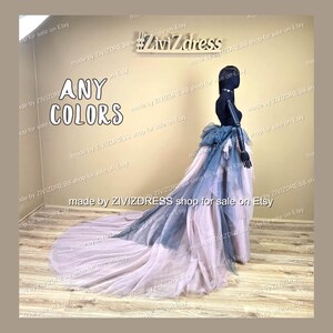 May include: A layered tulle skirt with a long train is displayed on a mannequin. The skirt features dusty rose, grey-blue, and darker blue accents. The text "ANY COLORS" is visible. The skirt is suitable for special occasions.