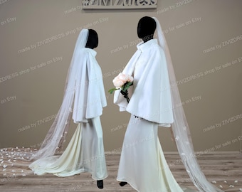 May include: Two white wedding dresses with long sleeves and a white faux fur cape. The dresses have a fitted bodice and a flowing skirt. One dress has a long white veil with a floral design. The dresses are displayed on mannequins in a studio setting. #ZiZdress