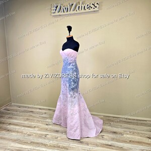 May include: A strapless, floor-length gown on a mannequin. The bodice is a light pink, transitioning to a blue and pink patterned skirt. The dress has a mermaid silhouette and a long train. The background includes the text "#Ziv7dress" and "made by ZIVIZDRESS shop for sale on Etsy."