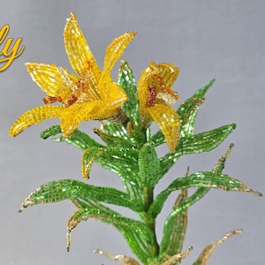 Op de afbeelding: Een handgemaakte gele lelie van kralen met groene bladeren en stelen. De afbeelding bevat tekst: "Yellow Lily", "Difficulty: ★★★" en "PDF Master Class". De cursus duurt 12 uur, heeft 40 pagina's en 70 foto's.