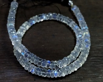 May include: A strand of white moonstone beads with iridescent blue flashes. The beads are faceted and have a slightly irregular shape. The strand is approximately 18 inches long.