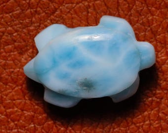 Könnte beinhalten: Eine kleine, blaue und weiße Schildkröte, geschnitzt aus einem blauen Chalcedon-Stein. Die Schildkröte ist etwa 2,5 cm lang und hat eine glatte, polierte Oberfläche.