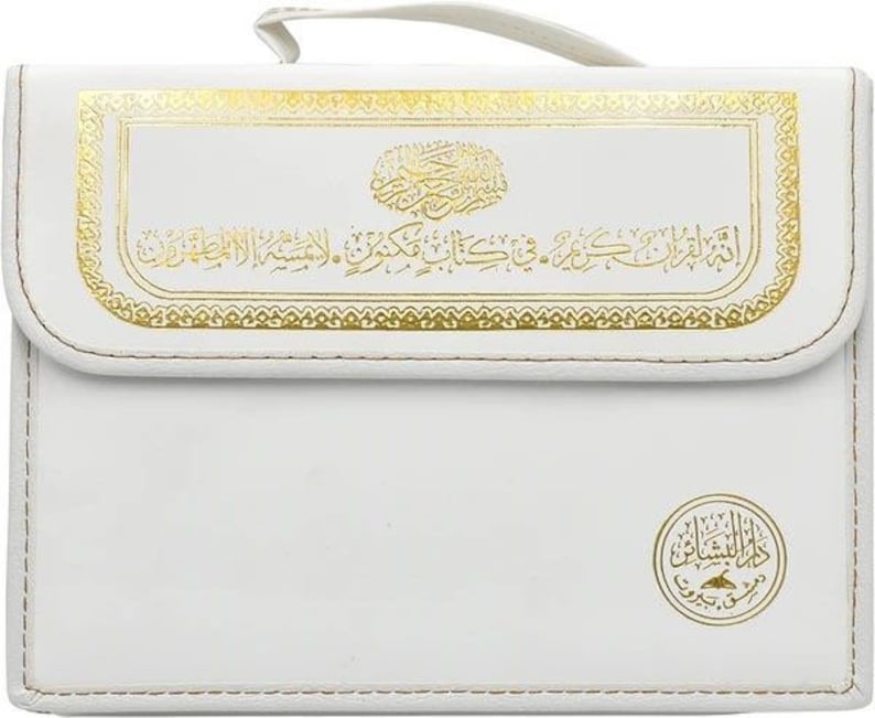 Puede incluir: Estuche rectangular blanco con detalles decorativos dorados y escritura &aacute;rabe. El estuche tiene un asa y un borde cosido. Un emblema dorado se encuentra en la esquina inferior derecha.