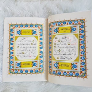 Puede incluir: Un libro abierto con bordes ornamentados y coloridos y escritura &aacute;rabe. Las p&aacute;ginas son de color crema y el texto es negro. El libro es probablemente un texto religioso, posiblemente el Cor&aacute;n, con caligraf&iacute;a detallada.