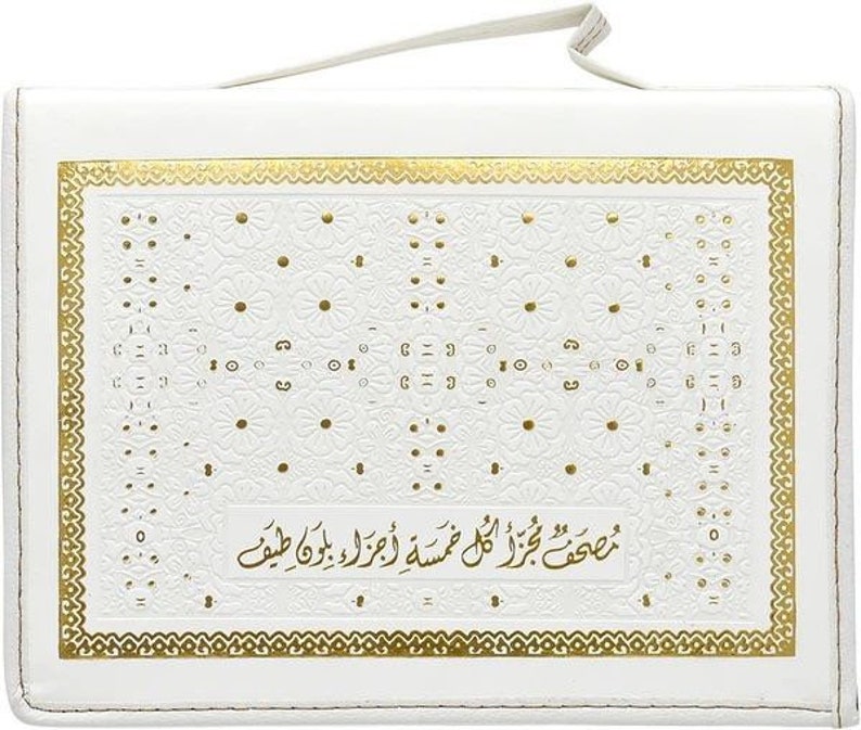 Puede incluir: Cubierta de libro rectangular blanca con un dise&ntilde;o floral dorado y un borde dorado. La cubierta tiene un asa en la parte superior. El texto de la cubierta est&aacute; en &aacute;rabe.