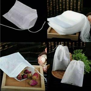 May include: White tea bags with a string for closing. The tea bags are shown in a stack and individually with loose tea leaves inside.