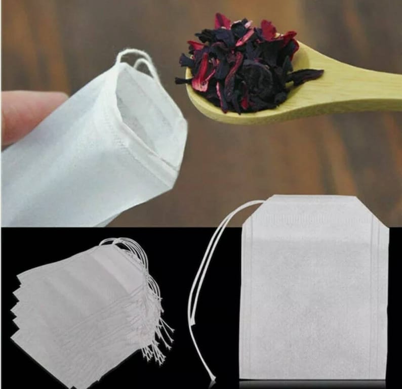 May include: A pack of 10 white tea bags with a drawstring. The tea bags are made of a fine mesh material and are perfect for loose leaf tea. The tea bags are shown next to a spoon filled with dried hibiscus flowers.