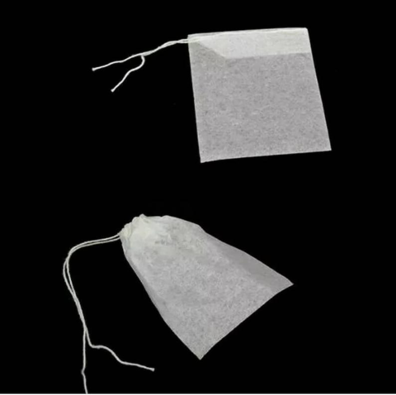 May include: Two white tea bags with strings. One tea bag is square and the other is a pouch shape.