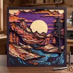 以下が含まれることがあります： 夕焼け時の山岳風景を描いた、多層構造の木製アート作品。 大きな丸い太陽、オレンジ、ピンク、茶色のグラデーションの山々、青い川が特徴です。 フレームは濃い茶色です。