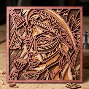 Könnte beinhalten: Ein quadratisches, mehrschichtiges Holzkunstwerk mit einem stilisierten Gesicht mit Stammesmustern und Musikinstrumenten. Das Kunstwerk verwendet Braun-, Beige- und Rosatöne mit einem dunkelbraunen Hintergrund und einem rosafarbenen Rahmen.