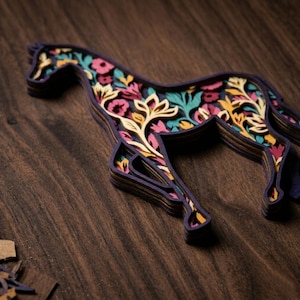 May include: A multi-layered wooden horse cutout featuring a dark purple outer frame and an intricate interior design filled with floral patterns in shades of teal, pink, yellow, and cream, creating a dimensional effect with visible stacked layers.
