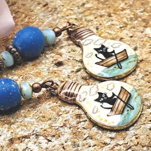 Boucles d'oreilles breloque émail chat dans une barque perles bleues petites puces bois foncé