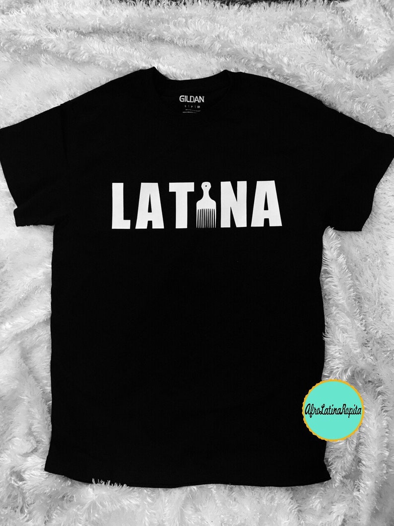 Puede incluir: Camiseta negra con la palabra "LATINA" en letras blancas y un peine blanco en el medio de la palabra.