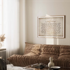 May include: A framed print with a beige background and gold Arabic calligraphy. The text is a list of the 99 names of Allah, also known as the Asma ul Husna. The print is hanging on a light beige wall above a brown couch.
