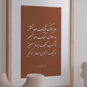 May include: A framed print with a brown background and white Arabic calligraphy. The text reads "Dawa'uk fiik wa ma tash'ur, wa da'uk ming wa ma tubsir, wa tahsib annaka jirm jism saghir, wa fiik an'tawi al-'alam al-akbar." The text is attributed to "Ali ibn Abi Talib".