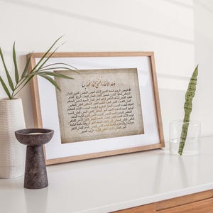 May include: A framed print with a beige background and Arabic text in black and brown. The text is a prayer in Arabic script. The frame is light brown wood.