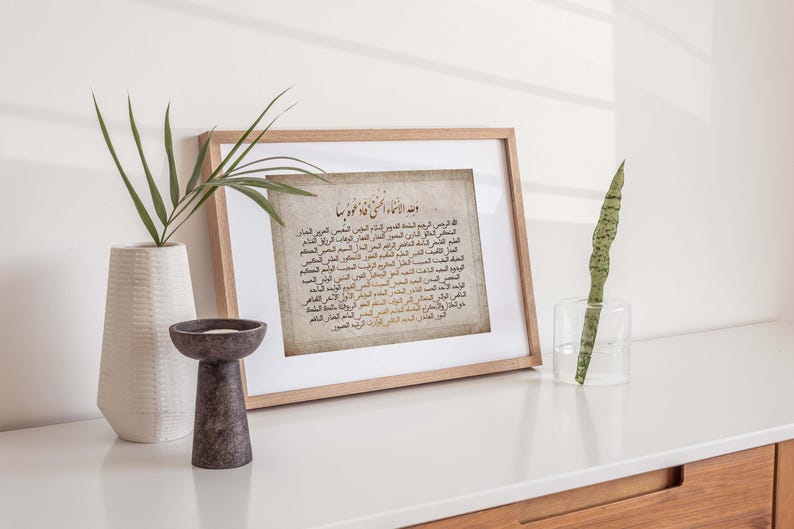 May include: A framed print with a beige background and Arabic text in black and brown. The text is a prayer in Arabic script. The frame is light brown wood.
