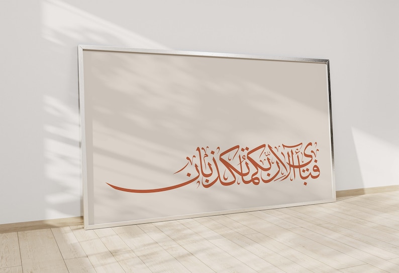 May include: A framed print with a white background and a brown Arabic calligraphy inscription. The inscription reads "فَإِذَا قُرِئَ الْقُرْآنُ فَاسْتَمِعُوا لَهُ وَأَنْصِتُوا لَعَلَّكُمْ تُرْحَمُونَ".