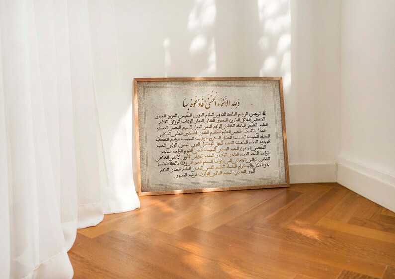 May include: A framed print with a white background and gold Arabic calligraphy. The text reads "وينه الانماء السنى فادعوه بها" which translates to "Where is the growth of the year, so call upon it".