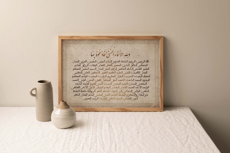 May include: A framed print with a beige background and brown text in Arabic script. The text reads "Waleed al-Asma al-Husna Fad'oho Baha" which translates to "And the names of the Most Beautiful, so call upon Him by them".