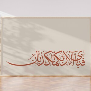 May include: A framed print with a beige background and a brown Arabic calligraphy inscription. The inscription reads "قُلْ هُوَ اللَّهُ أَحَدٌ".
