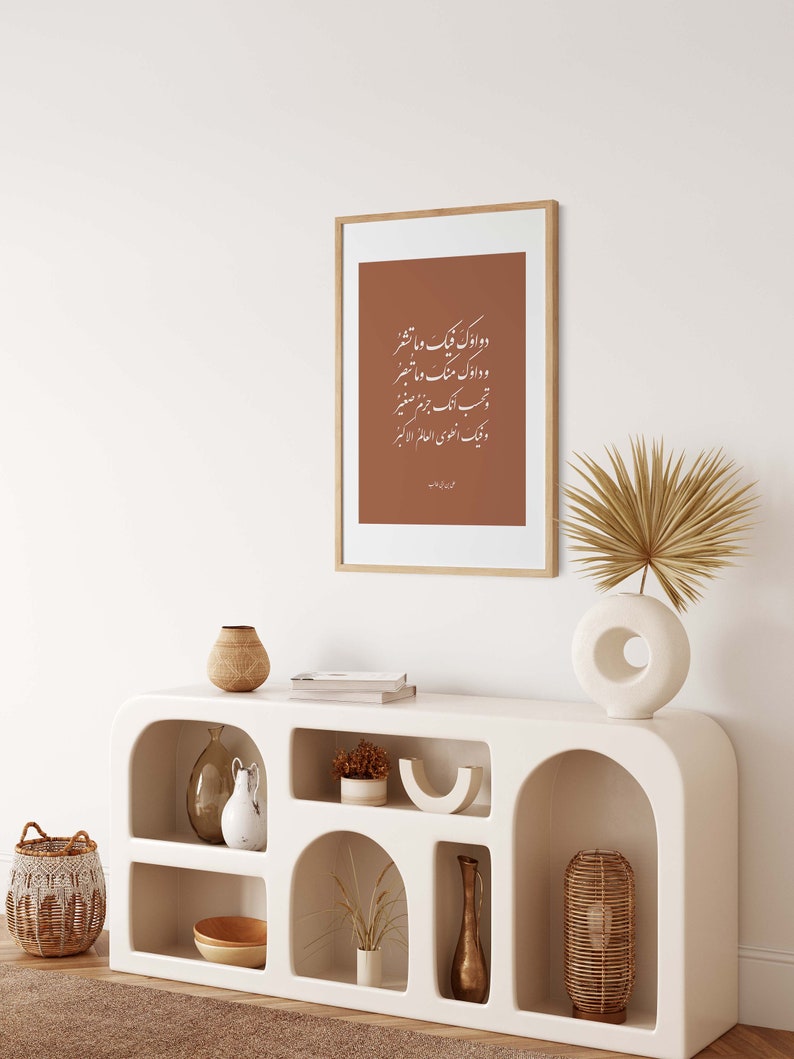 May include: A white, modern console table with arched shelves. The table is decorated with a framed print of Arabic calligraphy, a vase with dried pampas grass, a ceramic vase, a woven basket, and a gold vase.