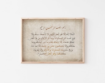 May include: A framed print with a beige background and gold Arabic calligraphy. The text reads "Allah la ilaha illa huwa al-hayy al-qayyum la ta'khudhuhu sinatu wa la nawm lahu ma fi al-samawati wa ma fi al-ardh man dhaliki yashfa'u 'inda hu illa bi'idhni ya'lamu ma bayna aydihim wa ma khalafhum wa la yuhithuna bishay'in min 'ilmihi illa bima sha'a wasi'a kursiyuhu al-samawati wa al-ardh wa la yat'uduhu hifzhuhuma wa huwa al-'alim al-'azim".