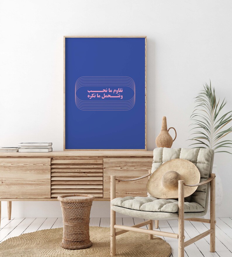 Pu&ograve; includere: Un poster incorniciato blu con una citazione araba rosa che recita "Impariamo da ci&ograve; che sperimentiamo e sperimentiamo ci&ograve; che impariamo." Il poster &egrave; appeso a un muro bianco sopra un mobile in legno.