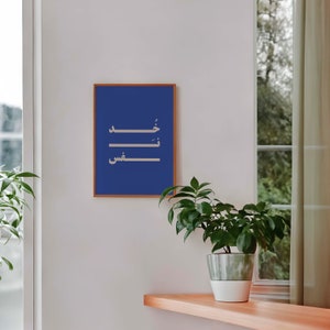 Puede incluir: Una impresi&oacute;n enmarcada con fondo azul y caligraf&iacute;a &aacute;rabe blanca. El texto dice "وَ خَلَقَ فِى السَّمَاءِ", que se traduce como "Y &Eacute;l cre&oacute; en los cielos".