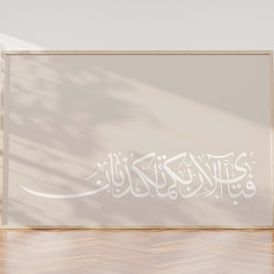 May include: A framed print with a beige background and white Arabic calligraphy. The calligraphy reads "فِي ظِلِّ الْعَرْشِ", which translates to "In the shade of the Throne".