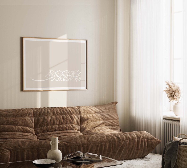 May include: A brown couch with a beige wall and a framed print with Arabic calligraphy in white on a beige background.