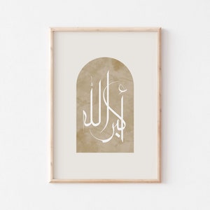 May include: A framed print featuring a beige background with a white Arabic calligraphy design in an arch shape. The calligraphy reads "Allah" in Arabic.