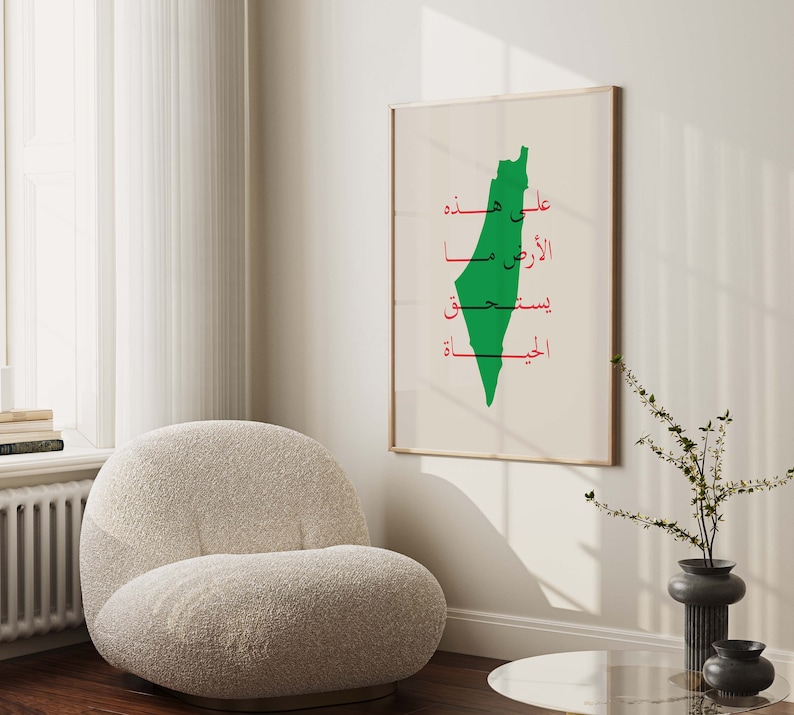 May include: A white framed poster with a green outline of the country of Palestine. The poster has Arabic text in red that reads "Upon the land, the right, the resistance, the liberation".