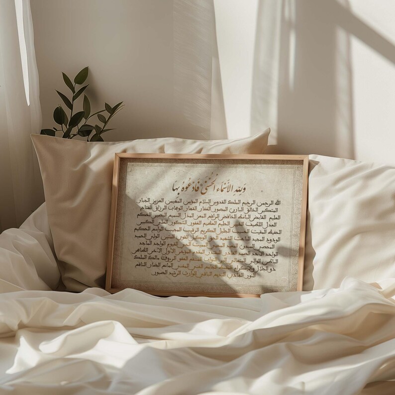 May include: A framed print with Arabic calligraphy in gold lettering on a white background. The text reads "Walahi Al-Asma'a Al-Husna Fa'du'uhu Biha" which translates to "And to Allah belong the most beautiful names, so call upon Him by them."