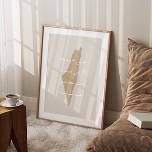May include: A framed print of the outline of Israel in beige with the words "על מפה" "الأرض" "فلسطين" "القدس" in white Arabic script.
