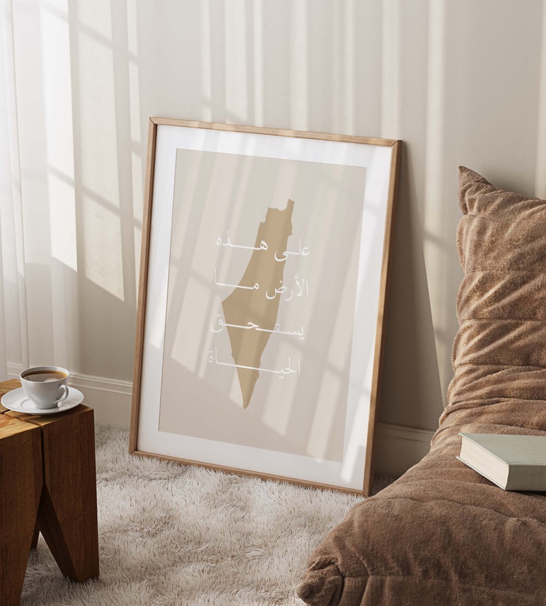 May include: A framed print of the outline of Israel in beige with the words "על מפה" "الأرض" "فلسطين" "القدس" in white Arabic script.