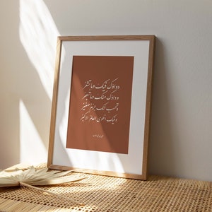 May include: A framed print with a brown background and white calligraphy in Arabic script. The text reads "دو اوک فیک و ما تشعر و دارک منگ و ما تبصر تحب ایک جرم صغیر ونيك العلوي العالم الاكبر".