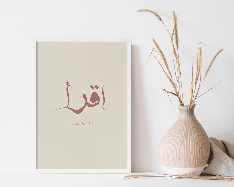 Puede incluir: Una impresi&oacute;n enmarcada blanca con un fondo beige. La impresi&oacute;n presenta la palabra &aacute;rabe para "leer" en caligraf&iacute;a marr&oacute;n. La palabra "leer" est&aacute; escrita en ingl&eacute;s debajo de la palabra &aacute;rabe.