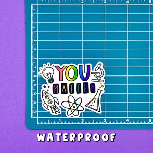 May include: A white sticker with the text "YOU MATTER" in rainbow colors. The sticker is surrounded by colorful illustrations of a lightbulb, a rocket, an atom, a microscope, and a beaker.
