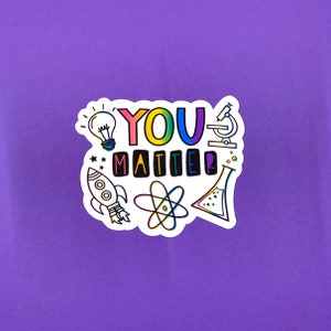 May include: A white sticker with the text "YOU MATTER" in rainbow colors. The sticker is decorated with various science-themed illustrations, including a lightbulb, a rocket, a microscope, an atom, and a beaker.