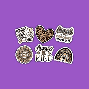 May include: Set of six leopard print stickers with various phrases, including "Positive Vibes Only", "Stay Wild", "Always Be Kind", "Leopard is my Favorite", and a heart and rainbow design.
