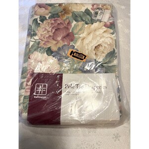May include: A package of Burlington pole top drapes. The drapes feature a floral pattern with large pink, cream, and purple flowers and green leaves on a cream background. The package is sealed in clear plastic.