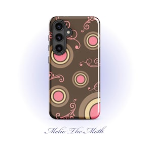 May include: A brown phone case with a repeating pattern of pink and tan circles and pink swirls. The phone case has a camera array on the top left. The text "Melio The Moth" is at the bottom.
