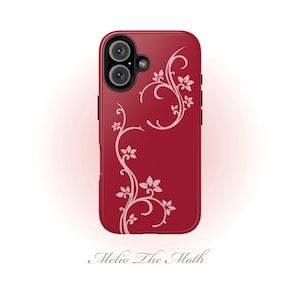 May include: A deep red smartphone case featuring a light pink floral vine pattern that curves along the side and top. The case has a dual-lens camera cutout at the top left corner. Below the case, the text Melio The Moth is printed in script.