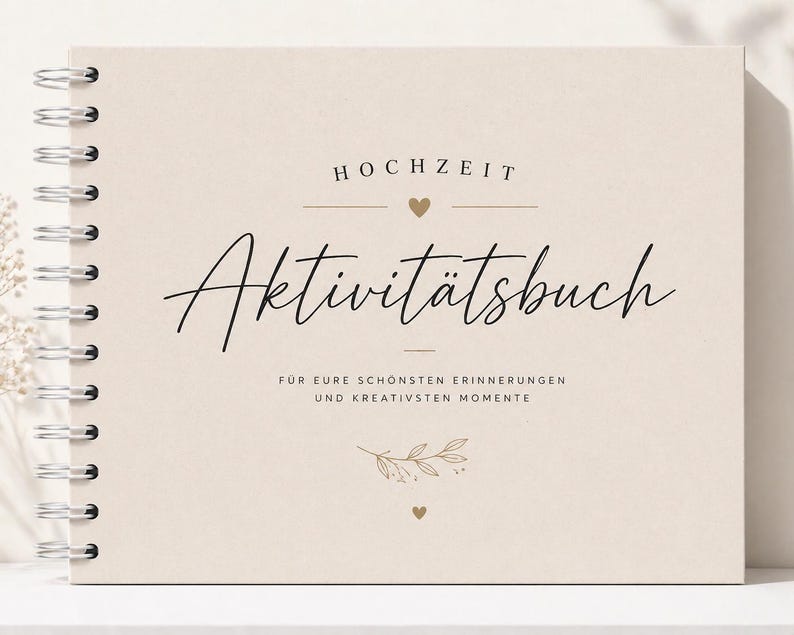 Puede incluir: Un libro de actividades con espiral y cubierta beige. La portada presenta la palabra "HOCHZEIT" sobre la palabra en cursiva "Aktivit&auml;tsbuch". Debajo, se lee "F&Uuml;R EURE SCH&Ouml;NSTEN ERINNERUNGEN UND KREATIVSTEN MOMENTE". Corazones dorados y detalles florales adornan la portada.